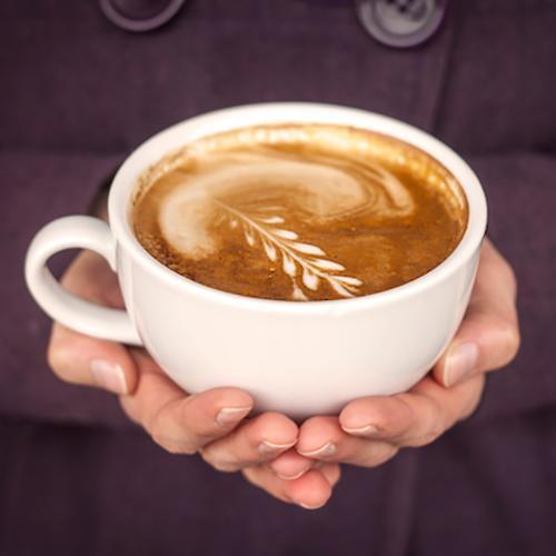 Close-up of hands holding a latte with latte art