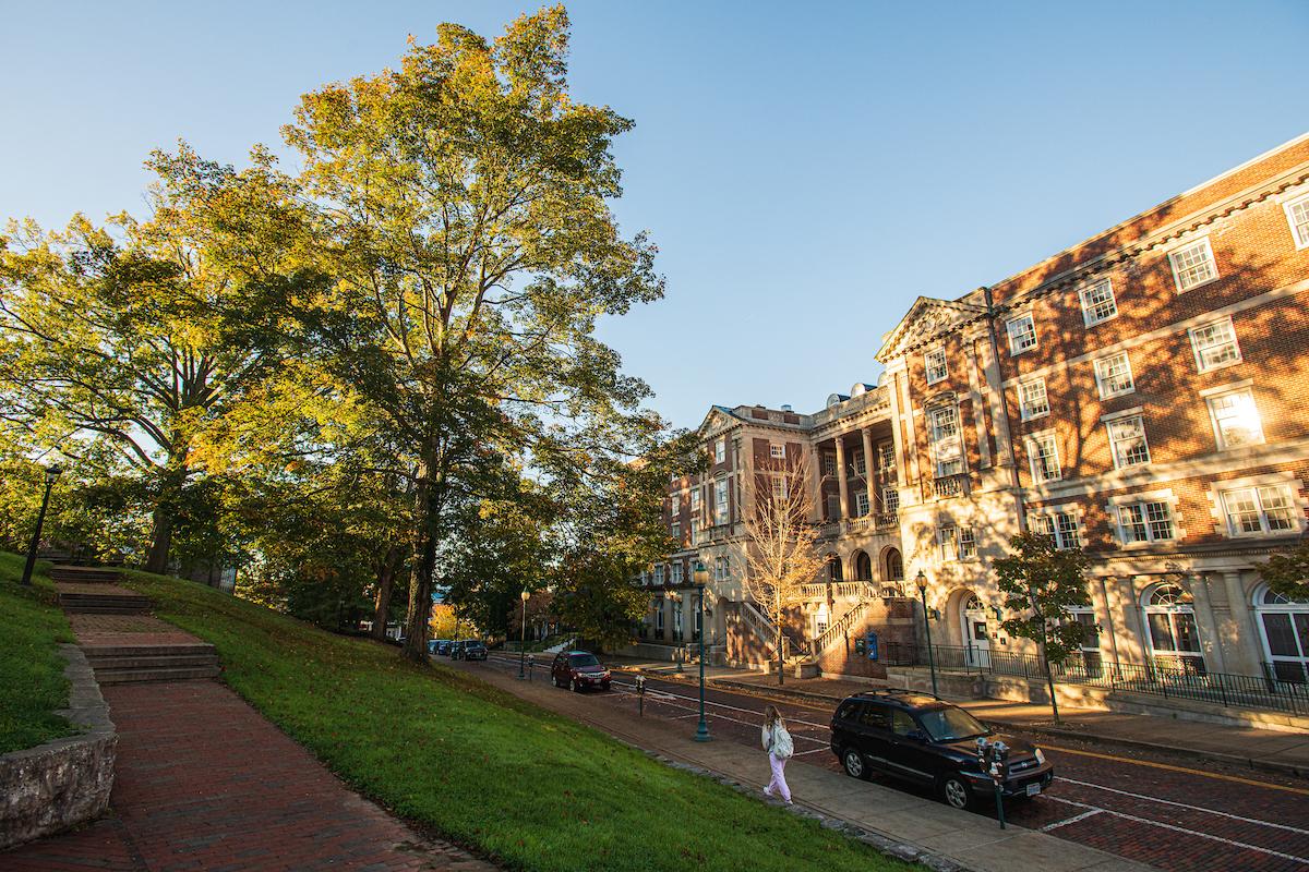 A student walks on the Athens Campus one fall morning, with brick buildings in the background