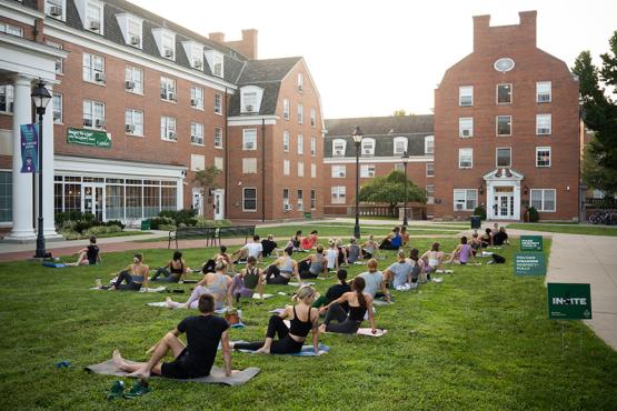 Dozens of Ohio University students practice yoga outdoors at sunrise