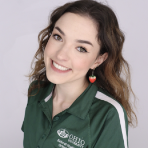 Lydia in a dark green Bobcat Student Orientation shirt, smiling at the camera.