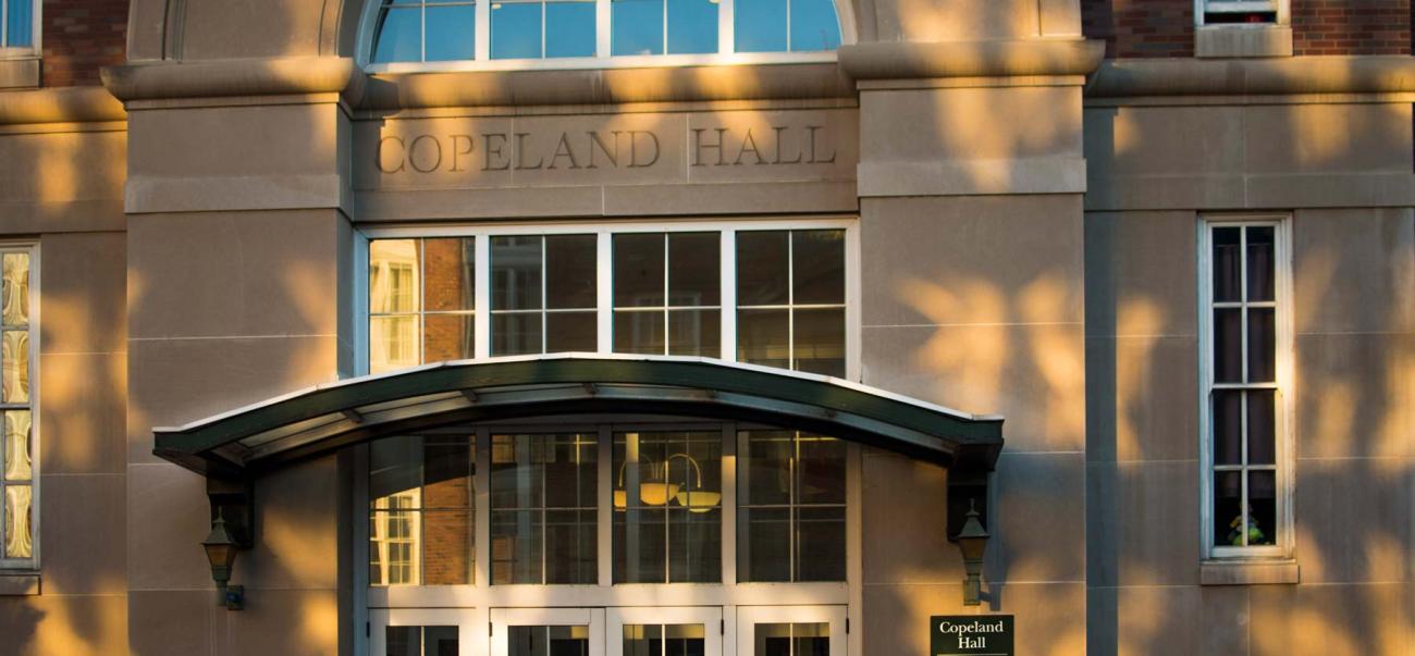 Front door on large building with awning and sign for "Copeland Hall" 
