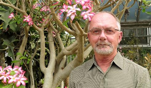 Harold Blazier, portrait with flowers in greenhouse