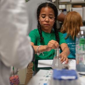 Young student stirring a beaker full of liquid in a lab