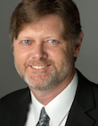 Headshot of a smiling David R. Moore in a suit and tie