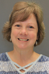 Headshot of a smiling Lisa Williams wearing a gray and white striped topmiling