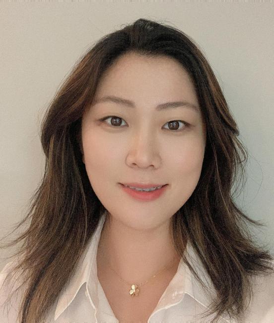 Headshot of a smiling Stephanie Huang wearing a cream colored blouse