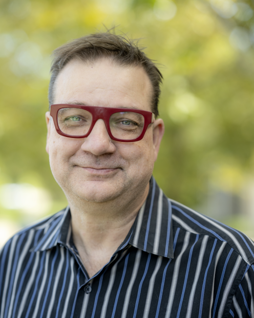 Headshot of Kevin Cordi, outside.  He is wearing a dark shirt with white stripes.