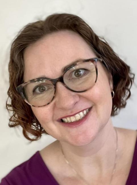 Headshot of a smiling Jennifer Lisy wearing glasses and a burgundy top. 