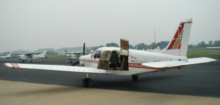 Piper Saratoga with open doors parked on landing strip