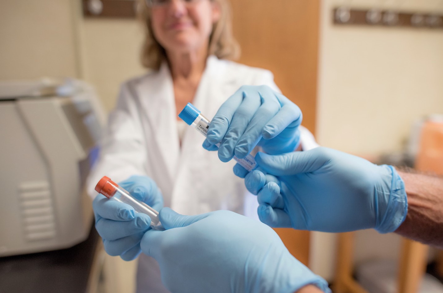 A person hands another person two vials.