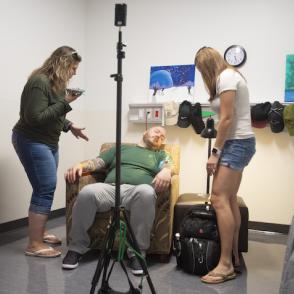 2 women helping a man slumped in a chair