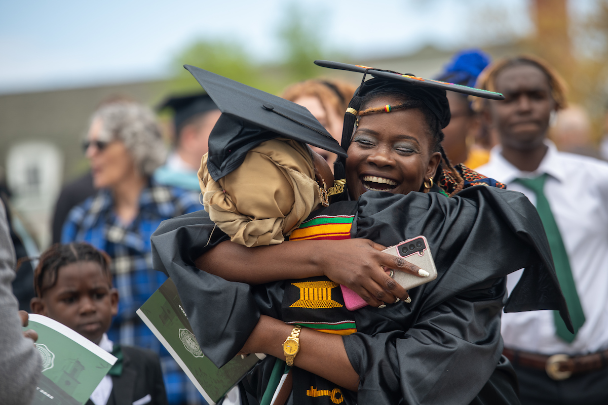 Two graduate students hug and celebrate after graduating