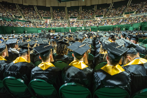 Students sit wearing their caps and gowns during Commencement