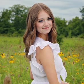 An image of Emily Stokes in a flower field with a white dress.