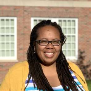 Dr. Harrison in a blue and white striped shirt with a yellow cardigan over it.