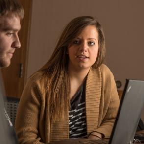 A person watching another use a laptop.