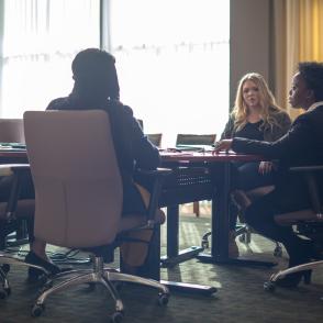 Meeting between several individuals at a large conference table.