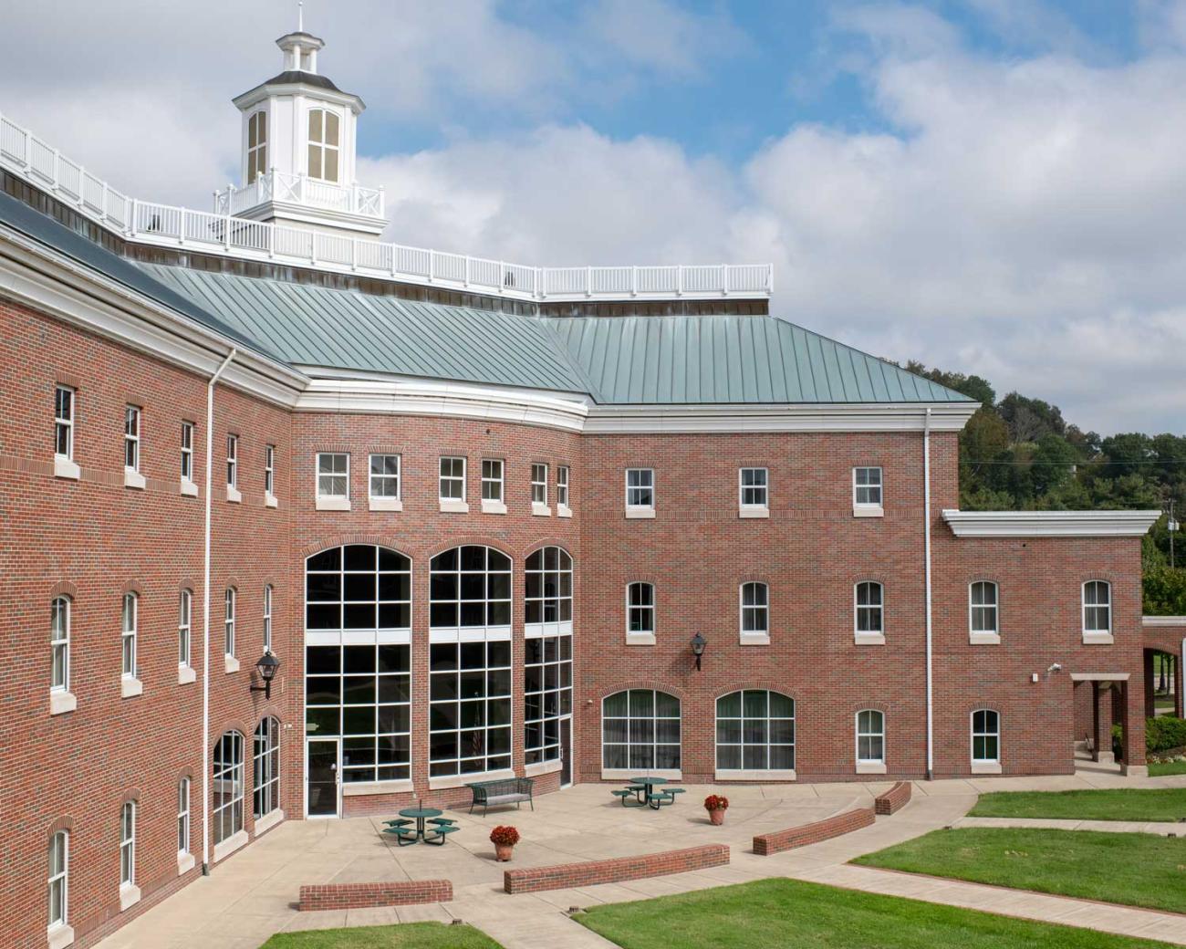 View of a large brick building with a green roof and arched windows