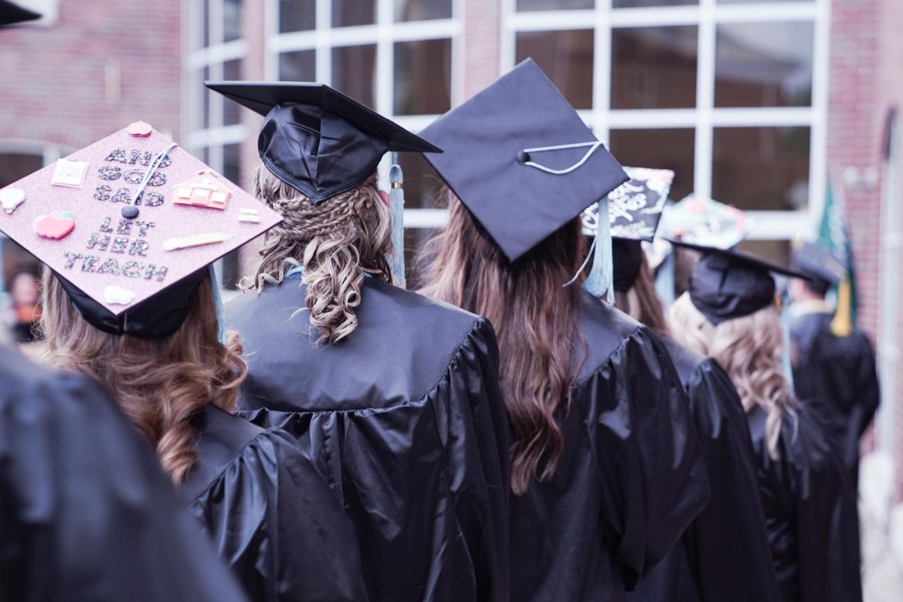 photo of graduates, back of several caps in a crowd