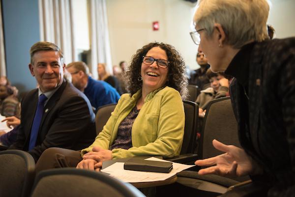 A shot of three people laughing at a thesis competition