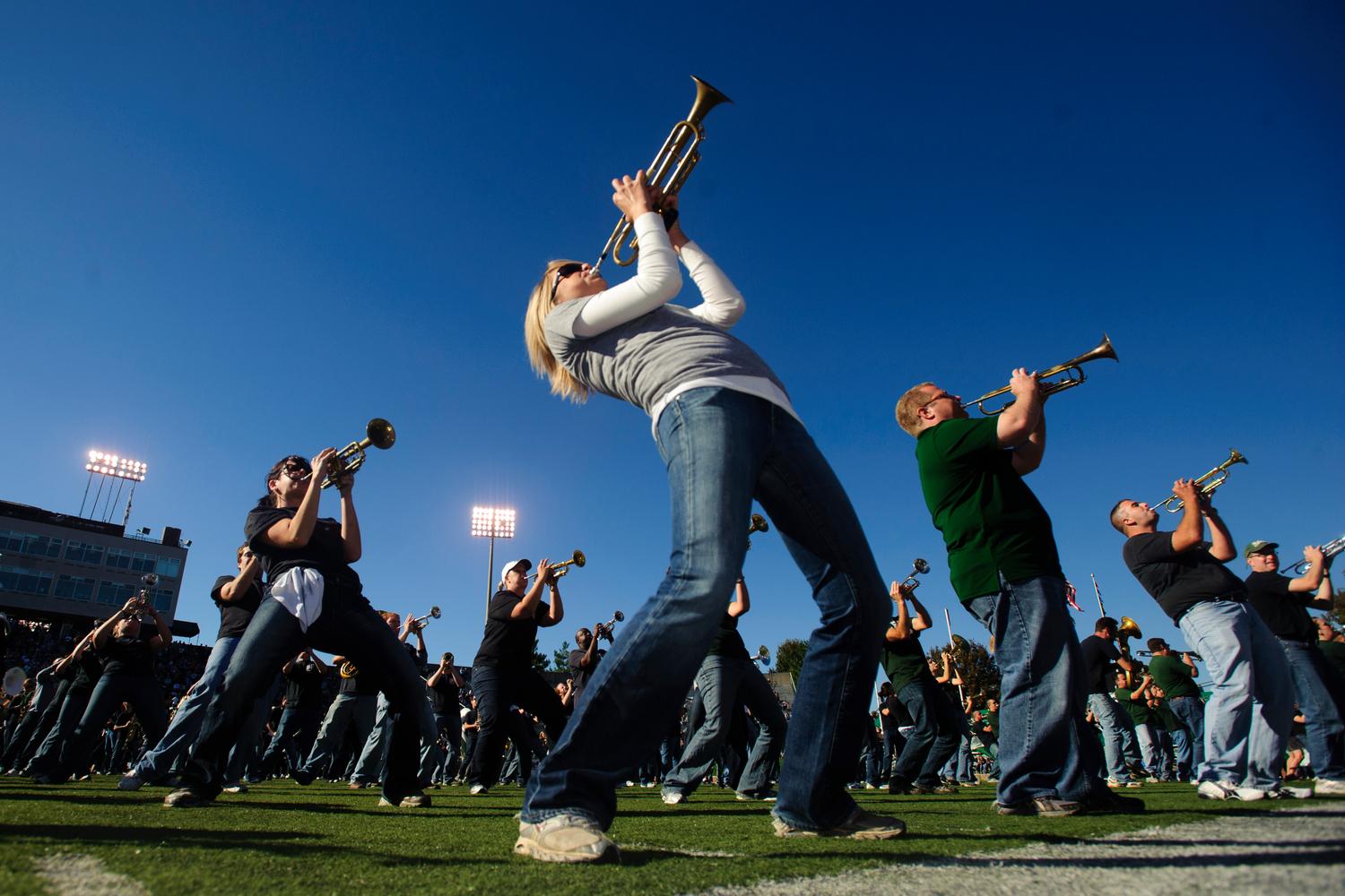 Marching 110 alumni play their horns on the field