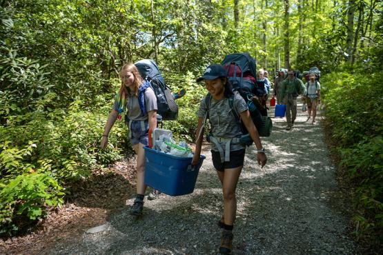 Ohio University students hike with backpacks on a forest trail