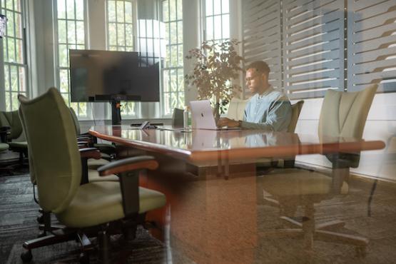 An Ohio University employee works on his laptop while sitting at a conference table in flexspace at The Ridges