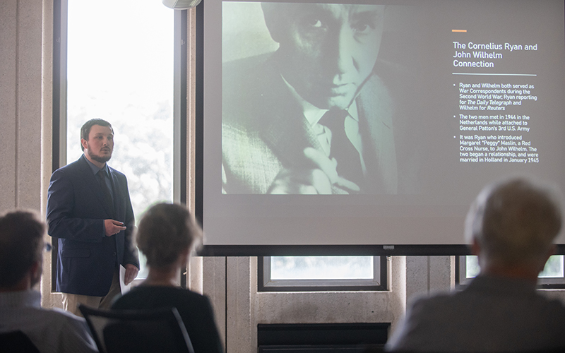 Someone gives a presentation in front of a screen in the Cornelius Ryan room at Alden Library