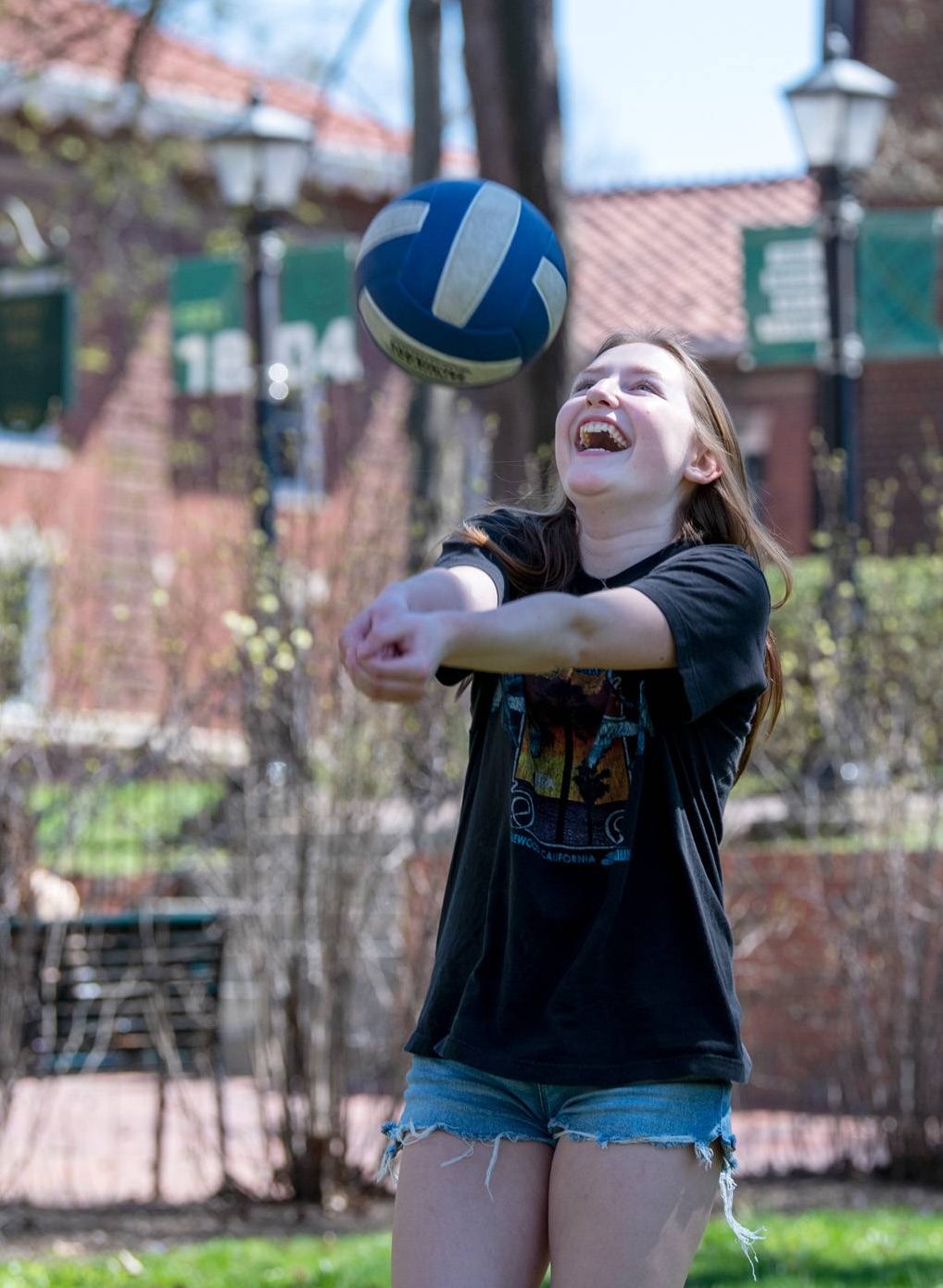 A student plays volleyball on College Green.
