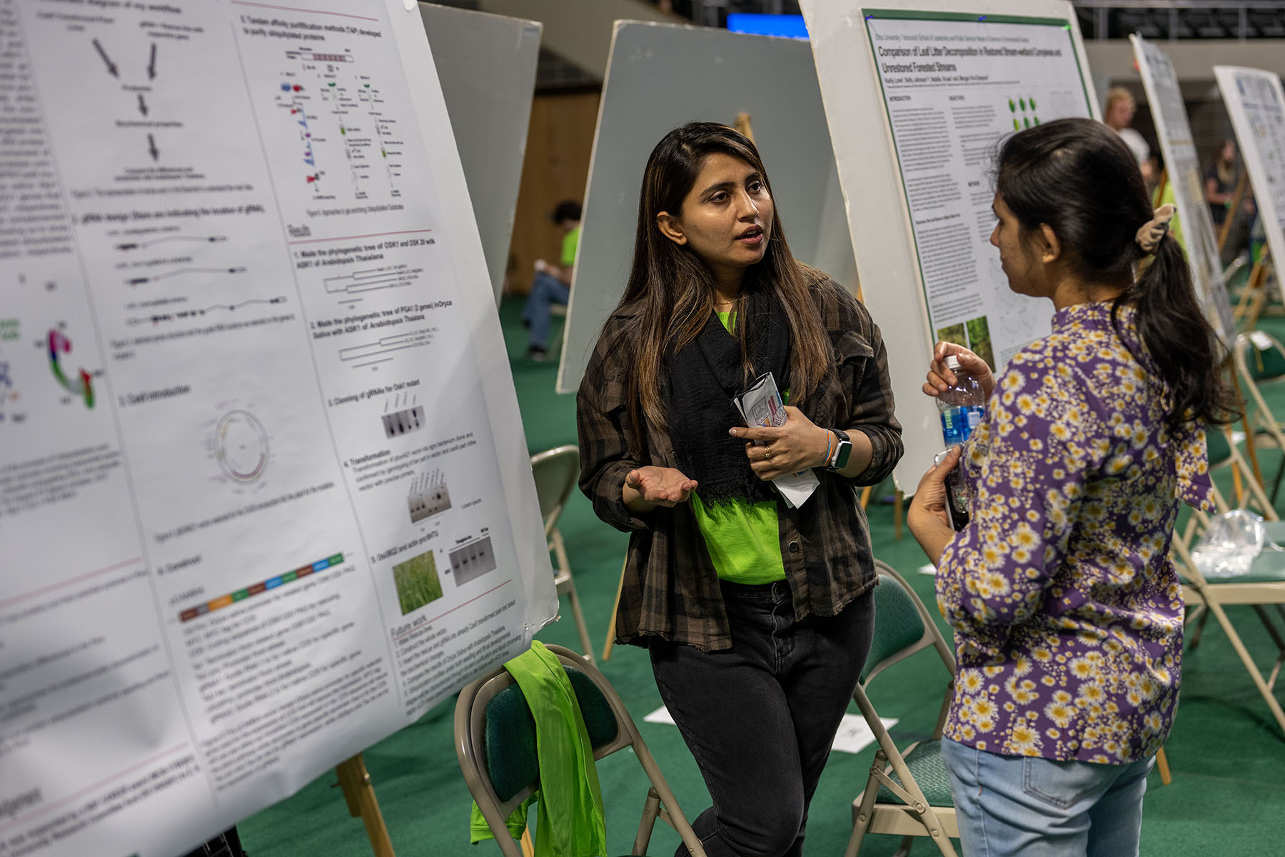 two students discuss a research project presentation displayed behind them