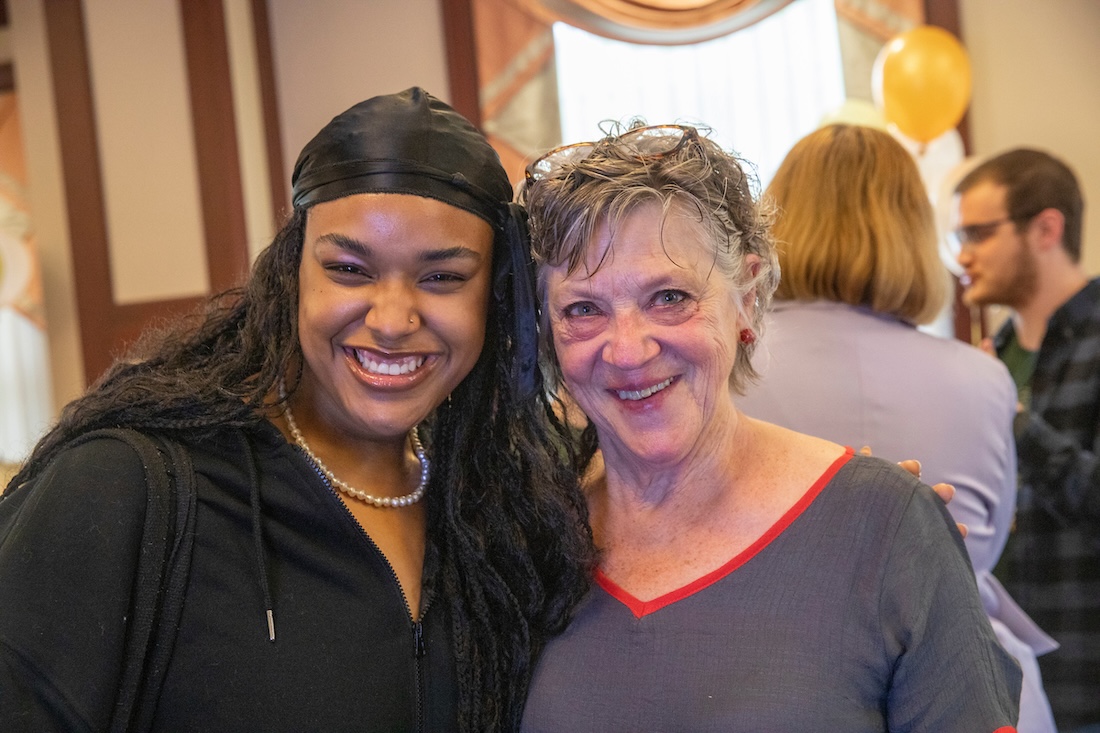 Two people stand side by side, smiling at the camera