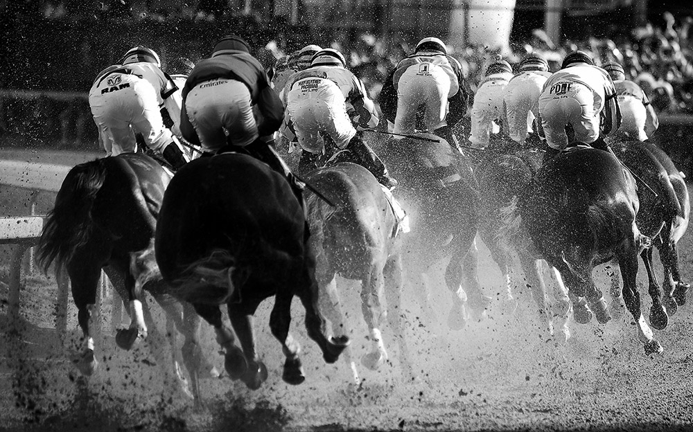black and white photo of horses and jockeys racing at the kentucky derby