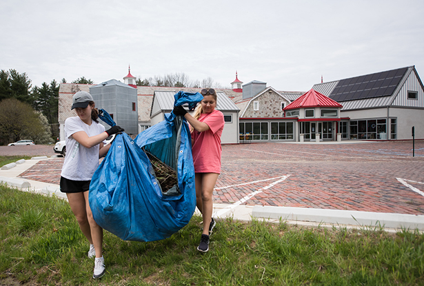 Ohio University students carry leaves, sticks and other debris that volunteers removed from the Dairy Barn Arts Center grounds.