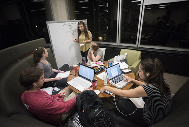 Students, who are working late in the evening, use a group study desk on the fourth floor of Alden Library to prepare for finals.