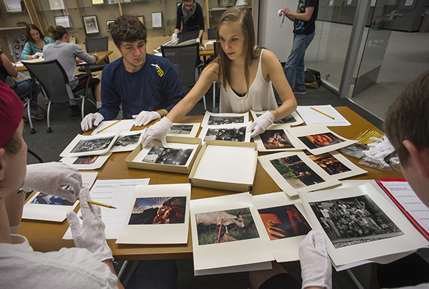 Students look through prints from the Lynn Johnson Collection housed in the Mahn Center as part of a visit to Alden Library by Tijah Bumgarner's Introduction to the Arts class.