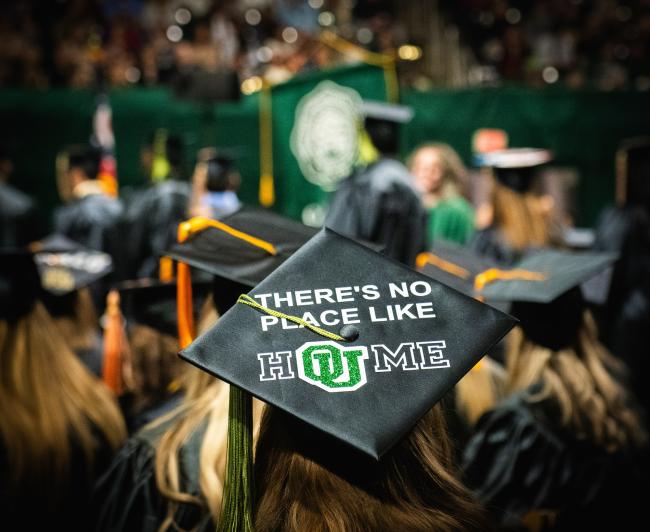 An OHIO's student is shown wearing a cap that says "There's No Place Like HOUME" at Commencement