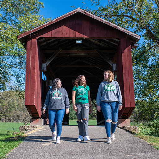 Three students walk through a barn.
