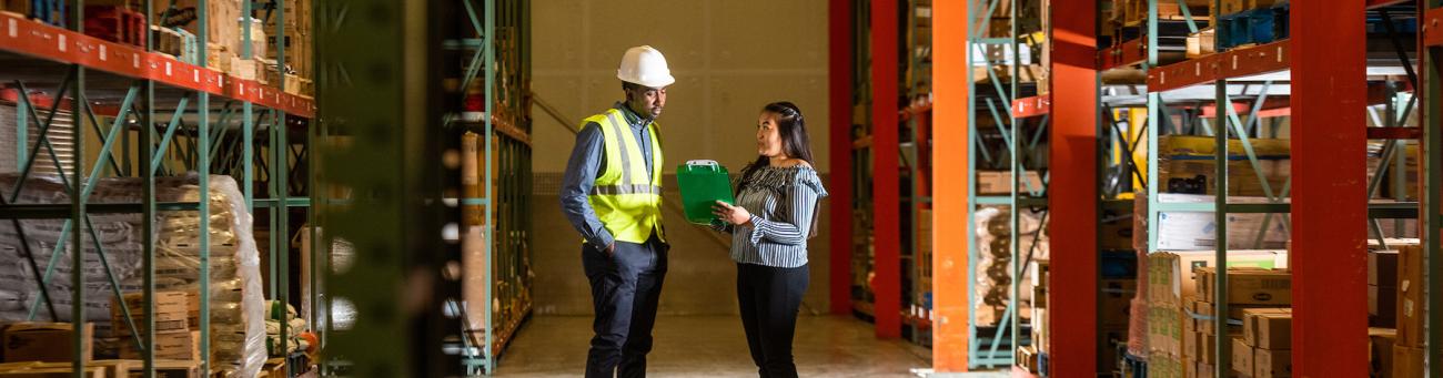 Two workers discuss a project in a shipping center.