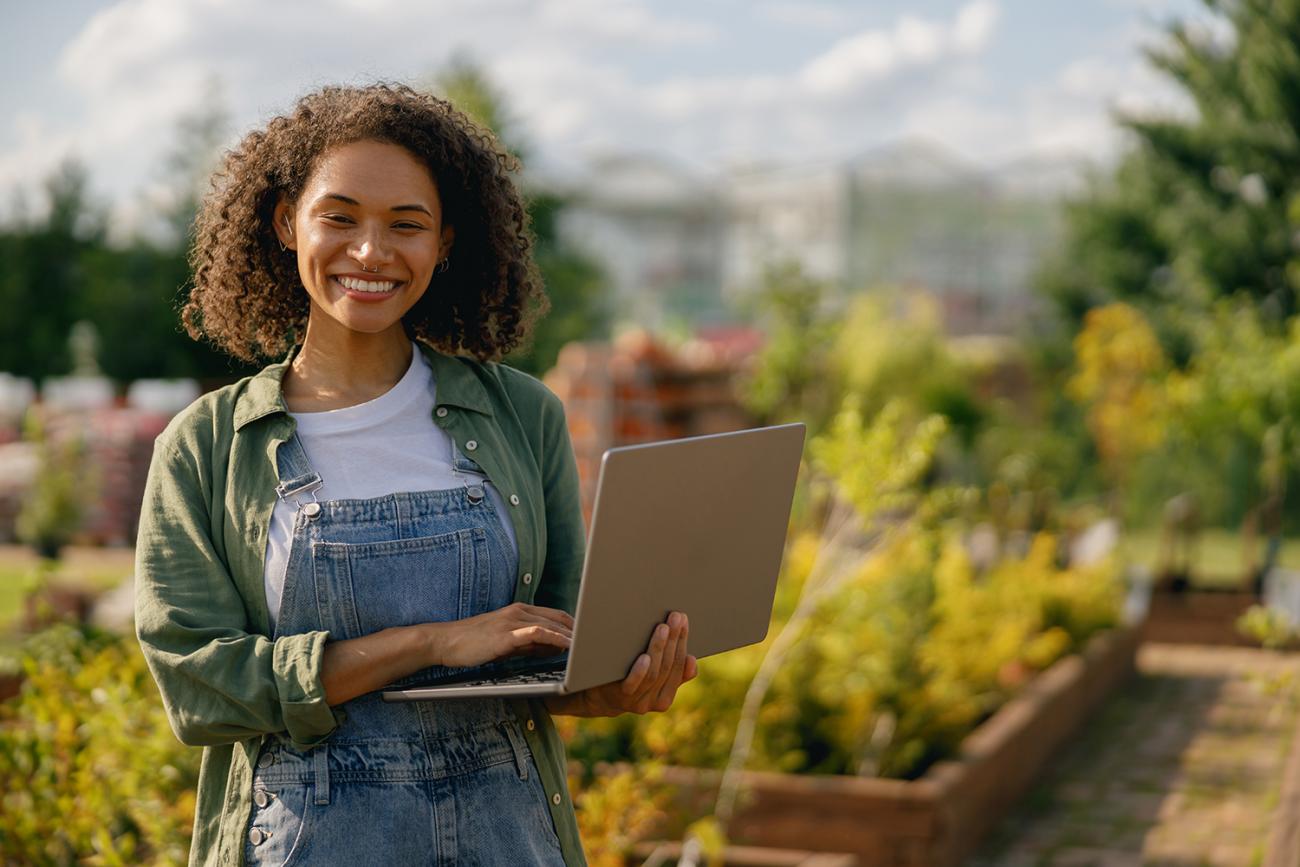 Woman standing in a garden area with a laptop