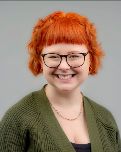 Headshot of Mo Jeffries in front of a gray background smiling and wearing glasses. 