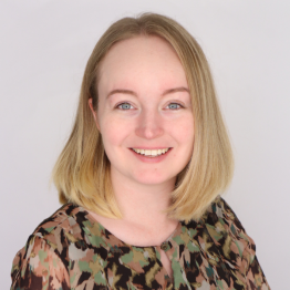 Julia smiling and sitting in a floral shirt in front of a white background