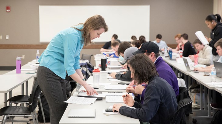 A professor works with students in a classroom