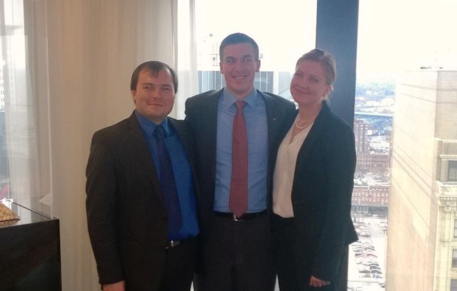 Three College of Business students pose in front of a window