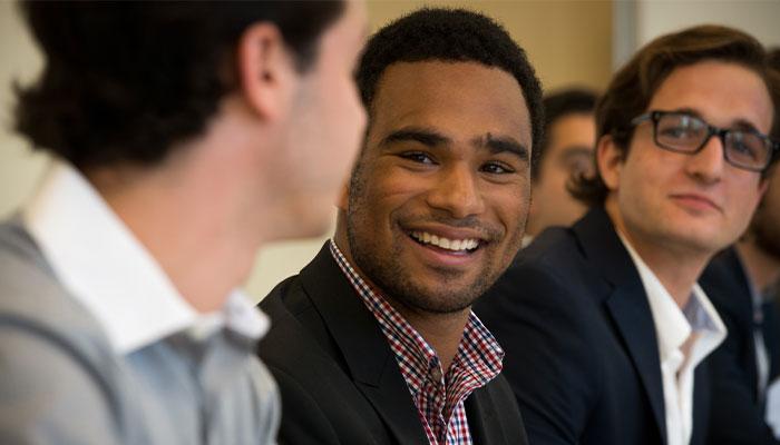 Graduate business students smiling and collaborating during an M B A program session