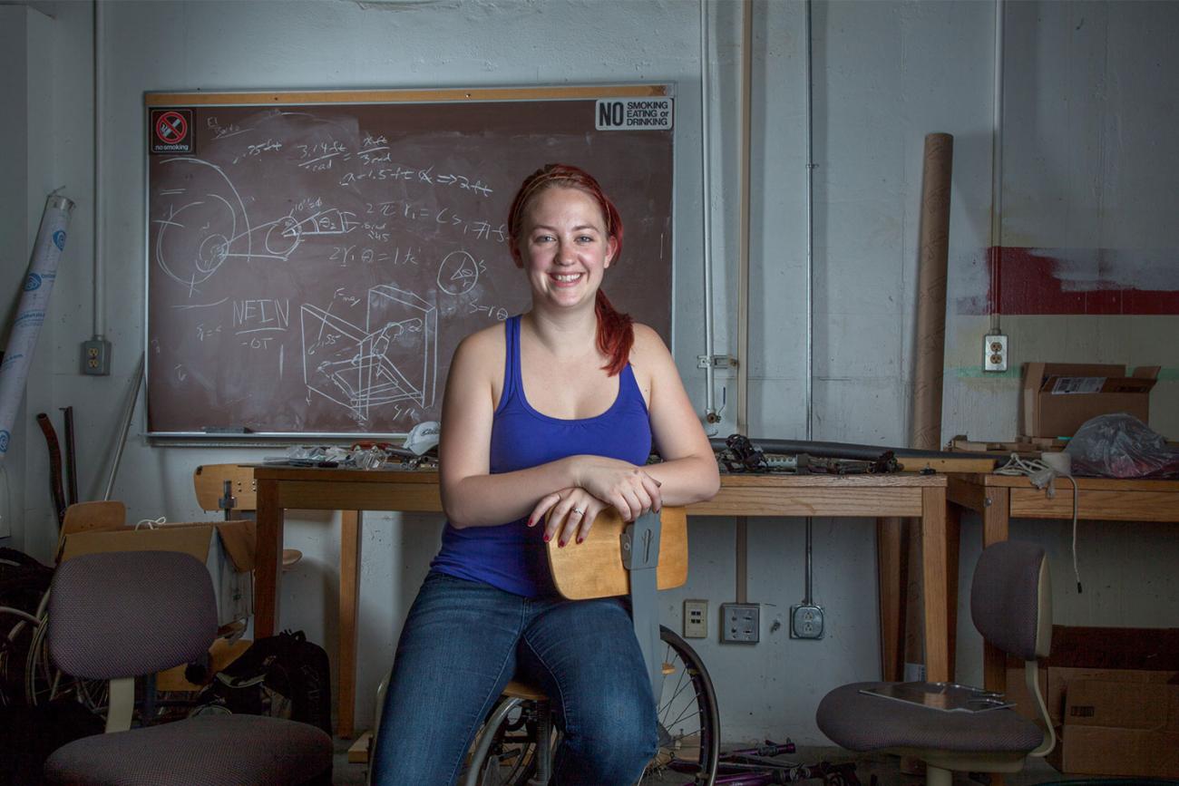 Smiling woman in blue tank top sitting in front of rustic table with chalkboard