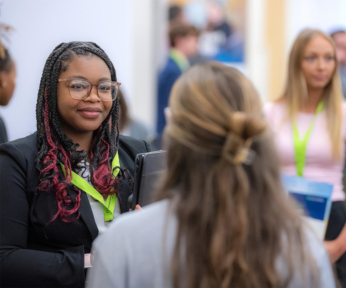 A business representative talks to a student at a job fair.