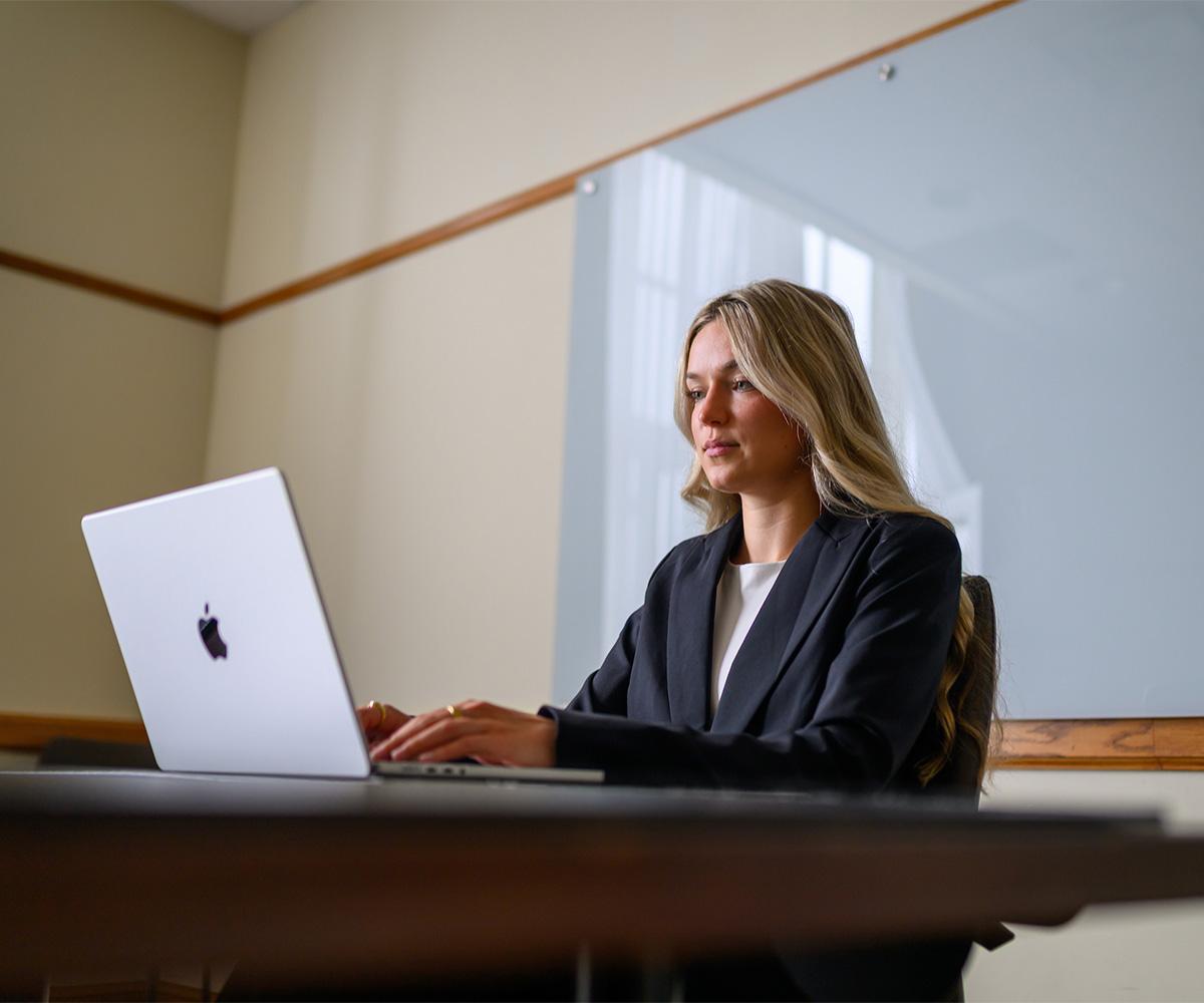 A student works at their laptop in a classroom.