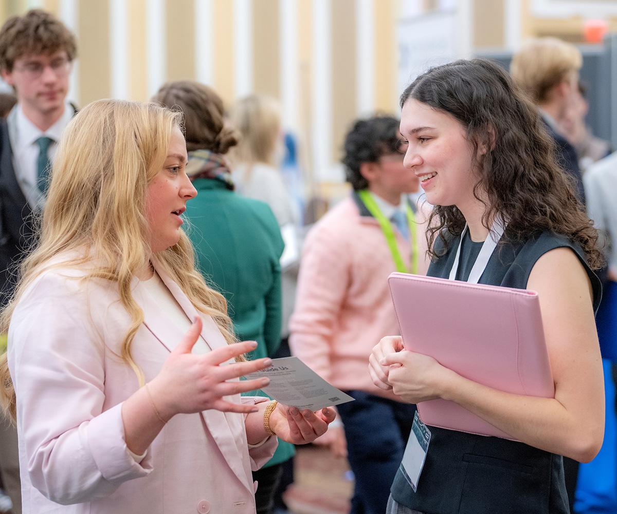 A business consultant talks to a student at a job fair.