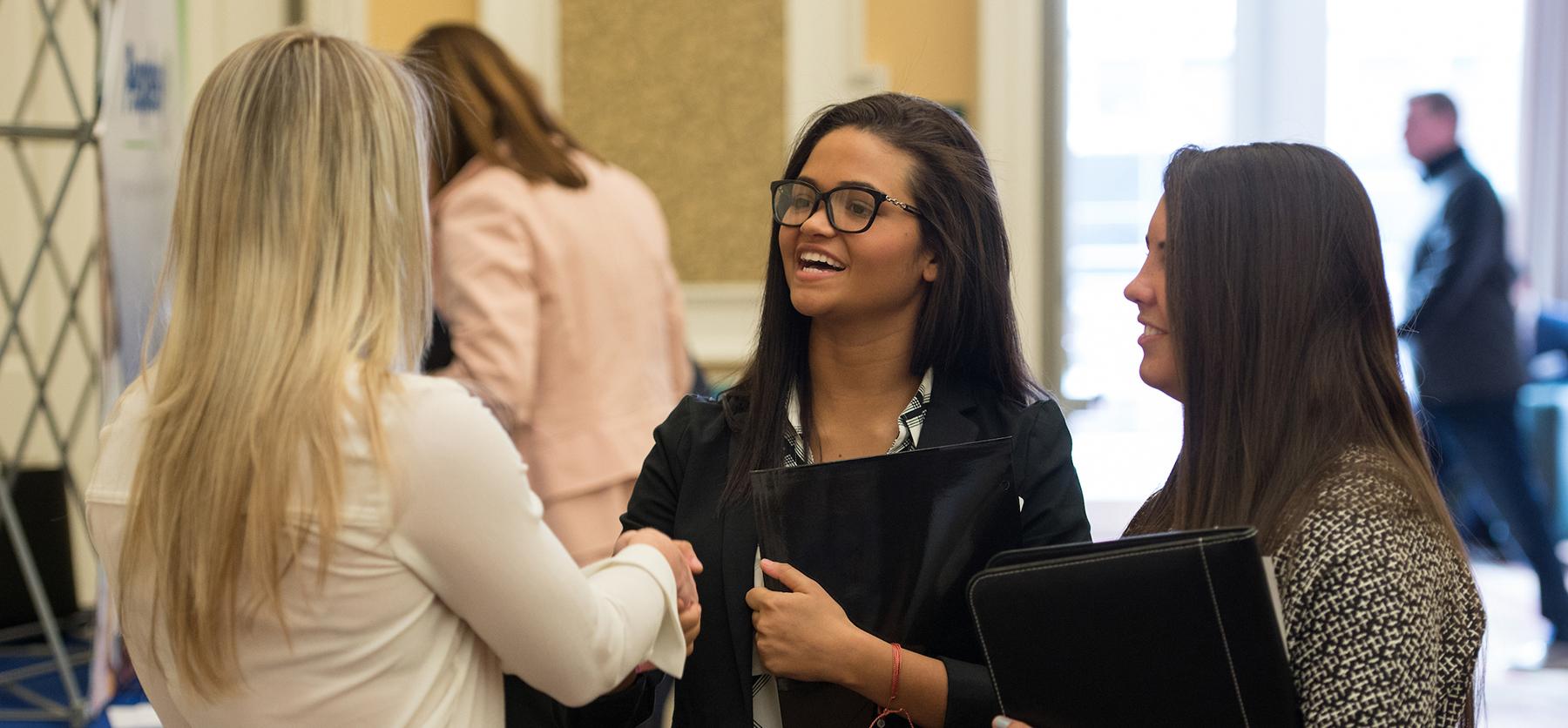 Business students shake hands at a career fair