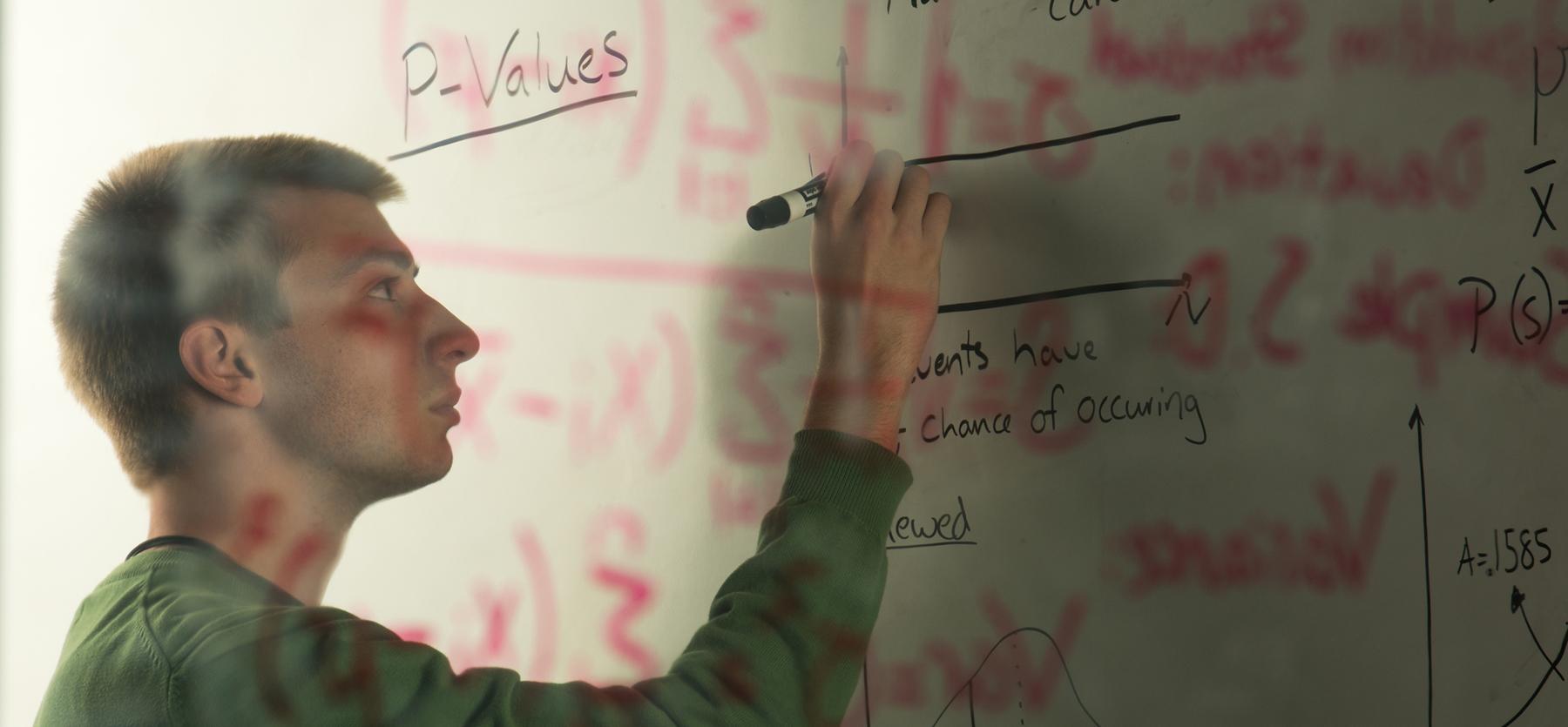 Student writes equations on a white board